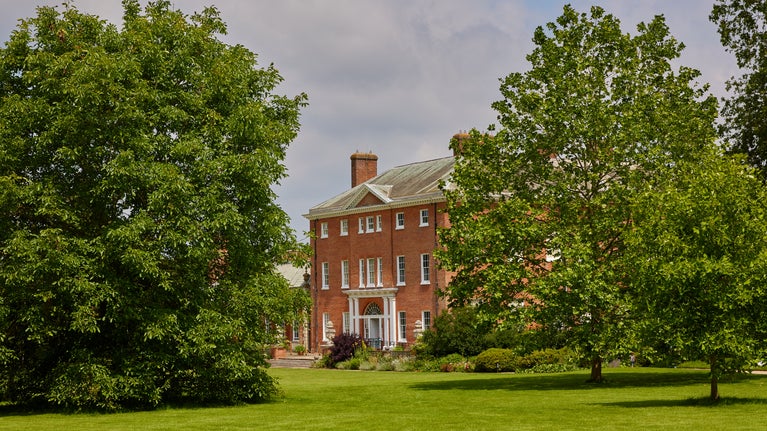 Exterior view of Hatchlands house with a lawn and trees in front of the house